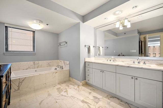 a spacious bathroom with a tub sink and mirror