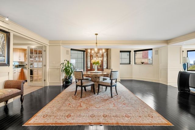 a living room with furniture a rug a chandelier and a table