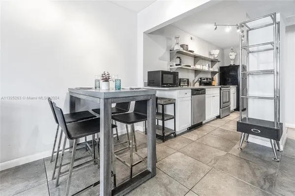 a kitchen with stainless steel appliances kitchen island granite countertop a table chairs sink and cabinets