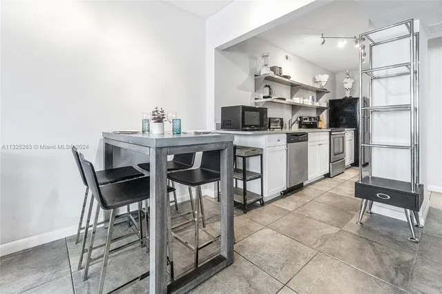a kitchen with stainless steel appliances kitchen island granite countertop a table chairs sink and cabinets