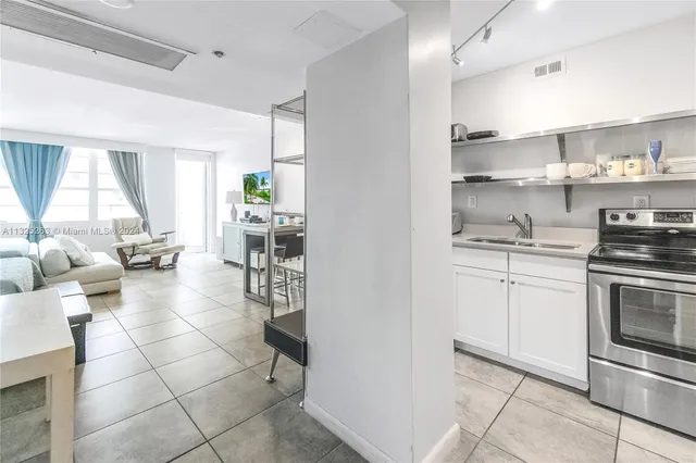 a kitchen with stainless steel appliances a stove a sink and white cabinets with wooden floor