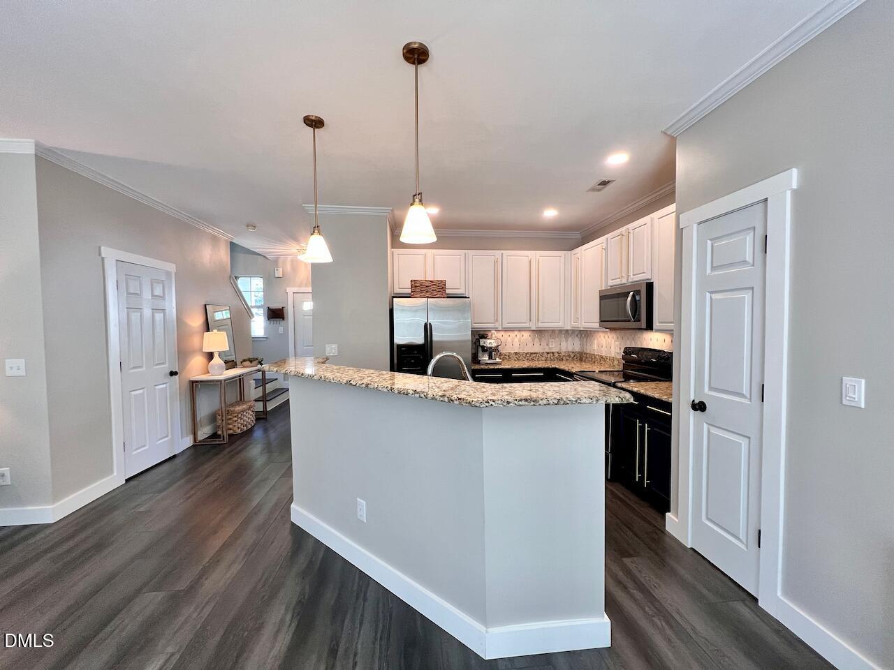 1941 Lost Lane Raleigh, NC 27603 - Photo 9 of 25 a kitchen with stainless steel appliances kitchen island a refrigerator a sink dishwasher a stove and white cabinets with wooden floor