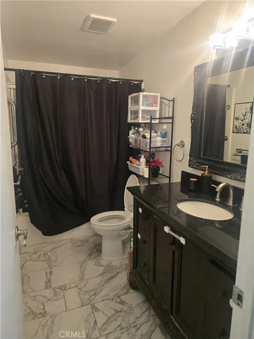 a bathroom with a granite countertop sink toilet and mirror