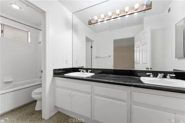a bathroom with a granite countertop sink a toilet and mirror