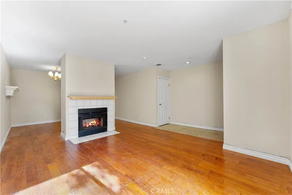 a view of an empty room with wooden floor a fireplace and a window
