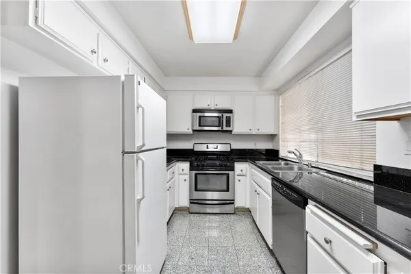 a kitchen with stainless steel appliances granite countertop a refrigerator and a sink