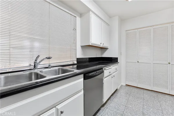 a kitchen with granite countertop white cabinets and sink