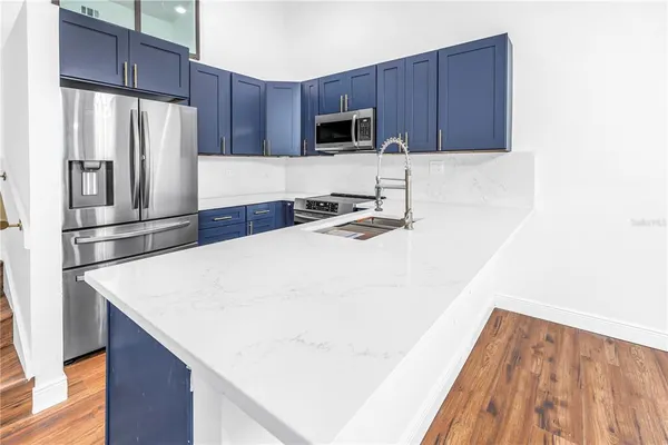 a kitchen with a sink a stove cabinets and wooden floor