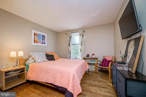 a bedroom with a bed and a flat tv screen on a dresser