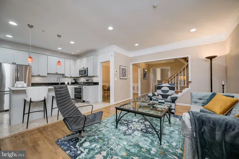 a living room with stainless steel appliances kitchen island granite countertop a couch and white cabinets