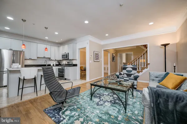 a living room with stainless steel appliances kitchen island granite countertop a couch and white cabinets