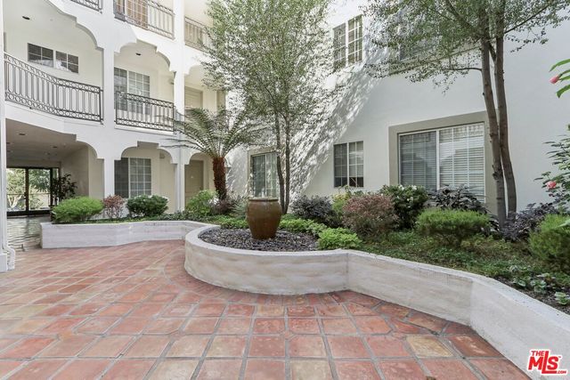 a view of a white house with a fountain and a potted plant