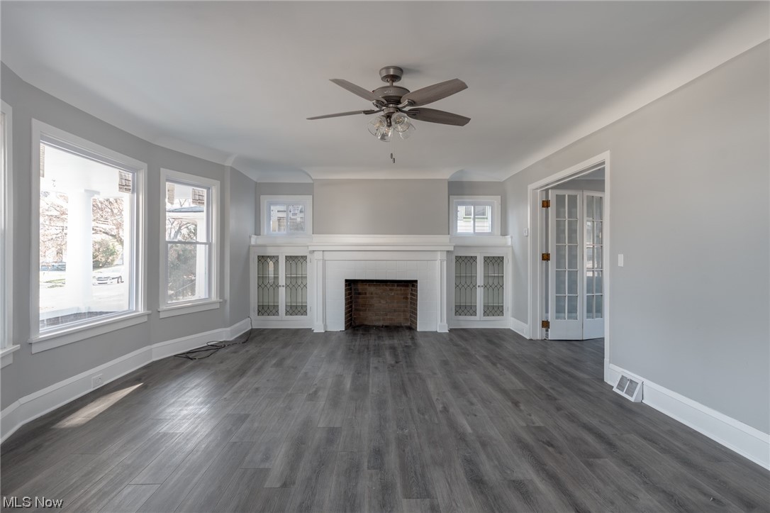 1228 Melbourne Road Cleveland, OH 44112 - Photo 3 of 35 Unfurnished living room with dark wood-type flooring, ceiling fan, and a fireplace