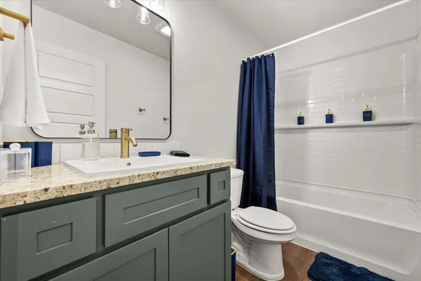 a bathroom with a granite countertop toilet sink and mirror