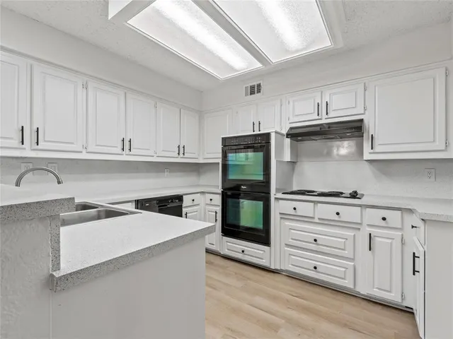 a kitchen with granite countertop a refrigerator stove and white cabinets