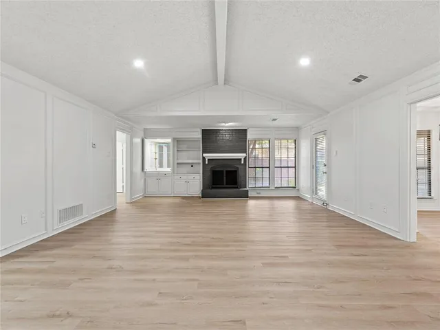 an empty room with wooden floor and fireplace