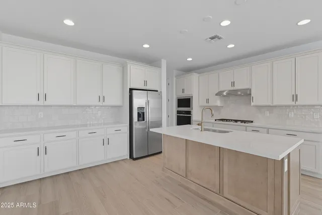 a kitchen with stainless steel appliances granite countertop a refrigerator and a stove top oven