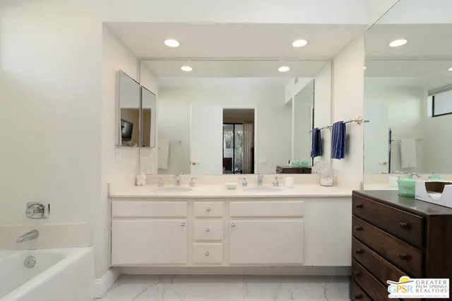 a bathroom with a double vanity sink a mirror and a bathtub