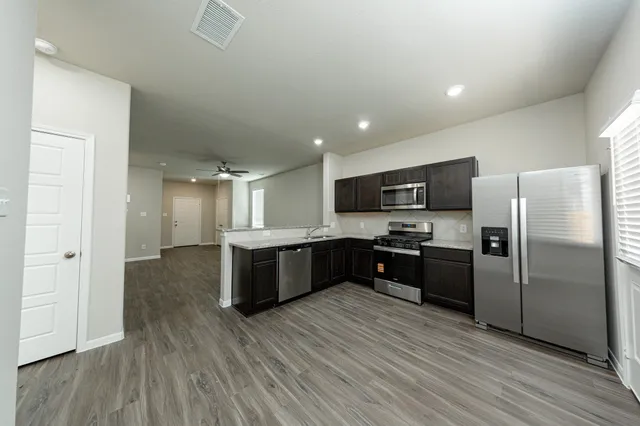 a large kitchen with a large counter top stainless steel appliances and wooden floor