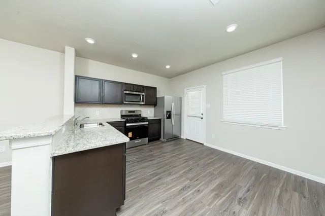 a kitchen with stainless steel appliances granite countertop a sink dishwasher stove and microwave with wooden floor