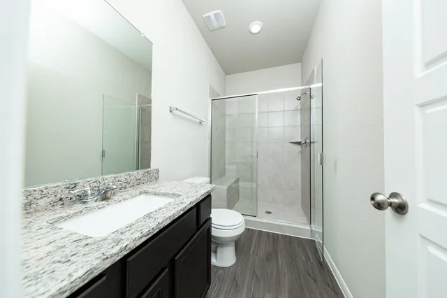 a bathroom with a granite countertop sink a toilet and shower