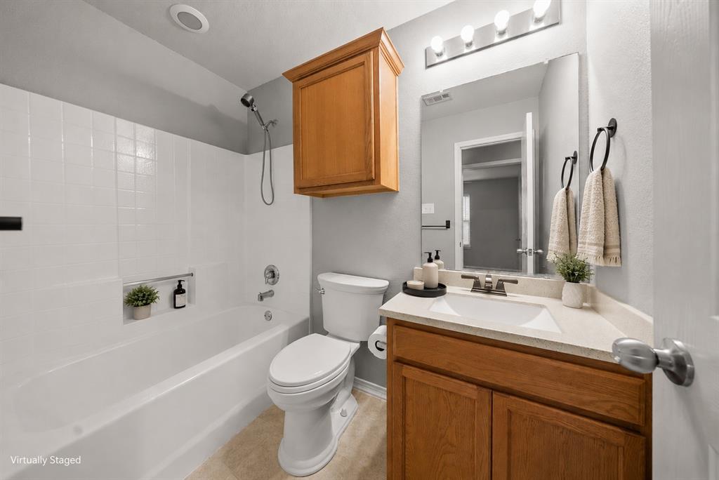 834 Hazel's Way Anna, TX 75409 - Photo 15 of 21 Full bathroom featuring a white tub/shower combination with an integrated niche, a wood-finish vanity with a single sink, a light-toned countertop, and tile flooring