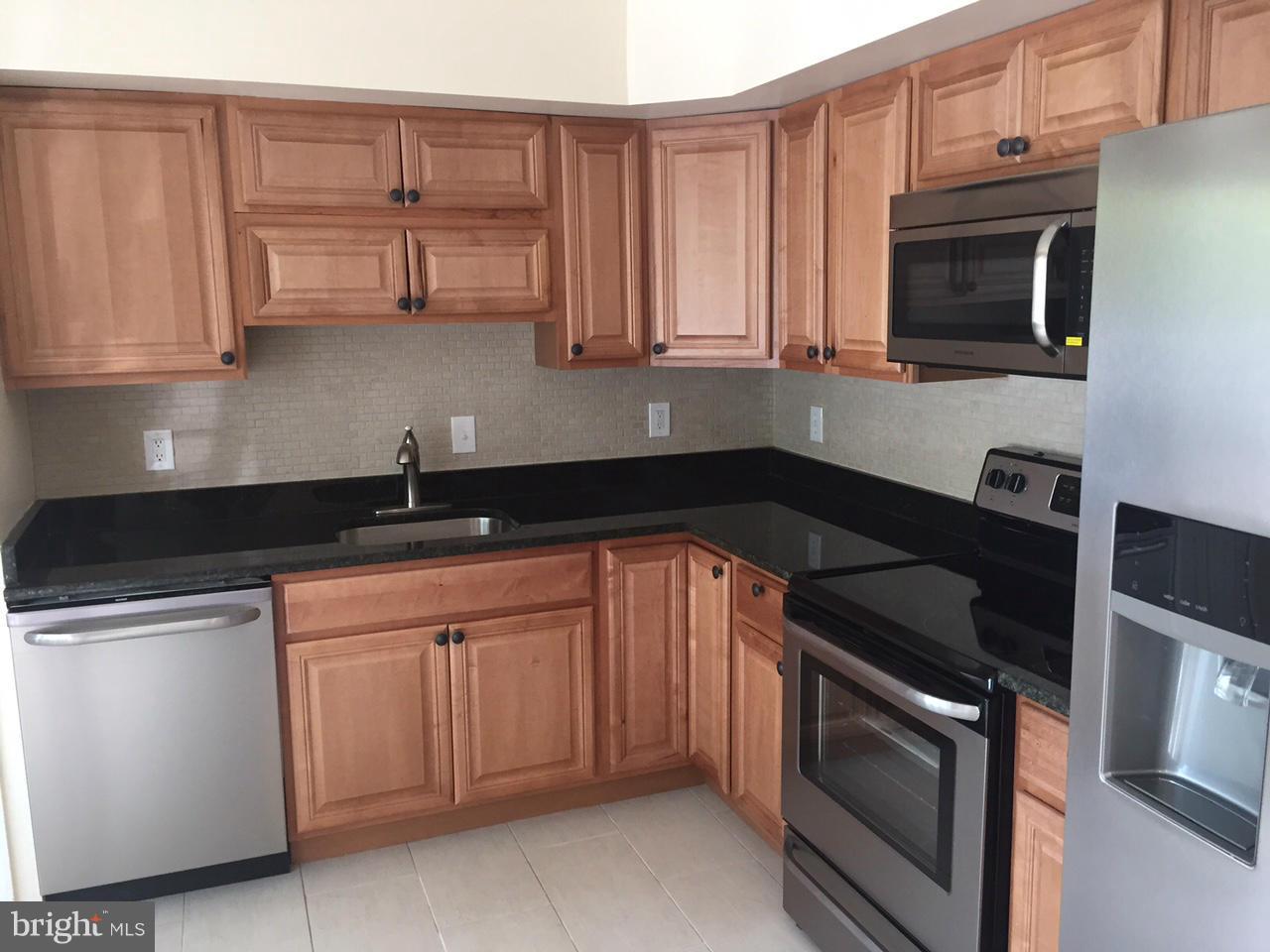 3623 Banquo Drive, Unit 62 Silver Spring, MD 20906 - Photo 2 of 5 a kitchen with stainless steel appliances granite countertop white cabinets and a stove top oven