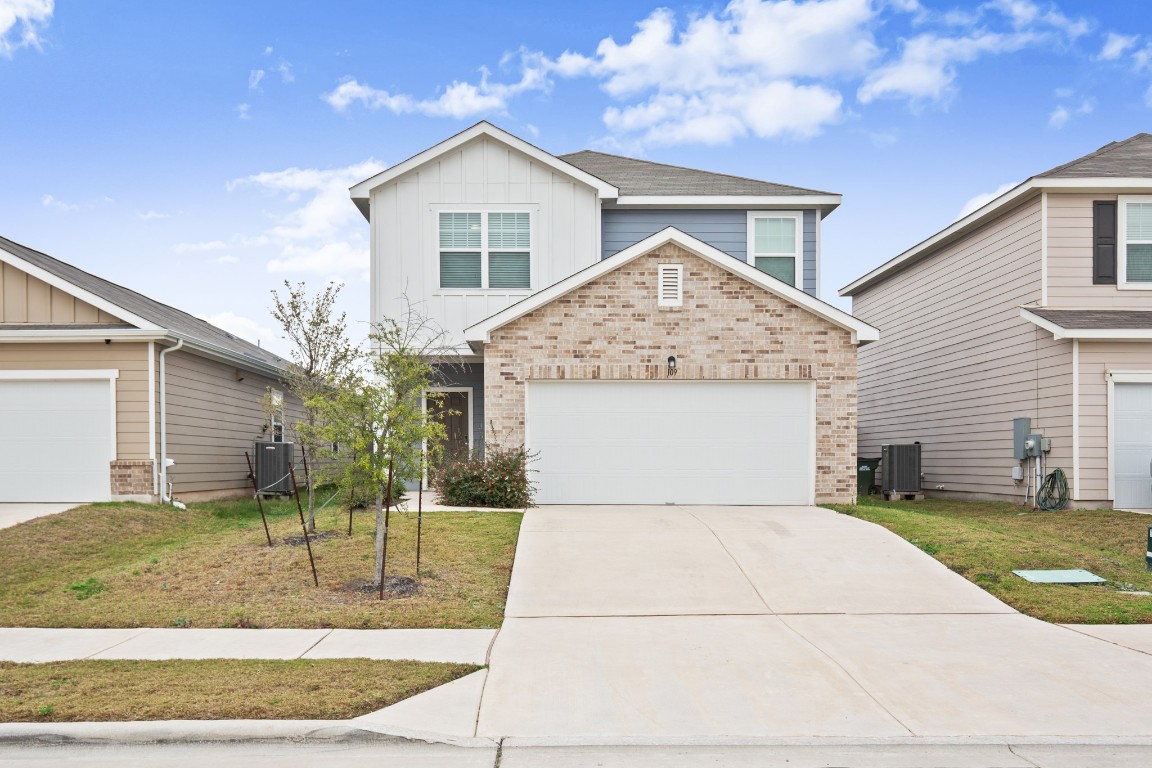 109 Gray Fox Loop Hutto, TX 78634 - Photo 1 of 28 View of front facade with brick siding, board and batten siding, concrete driveway, and a front lawn