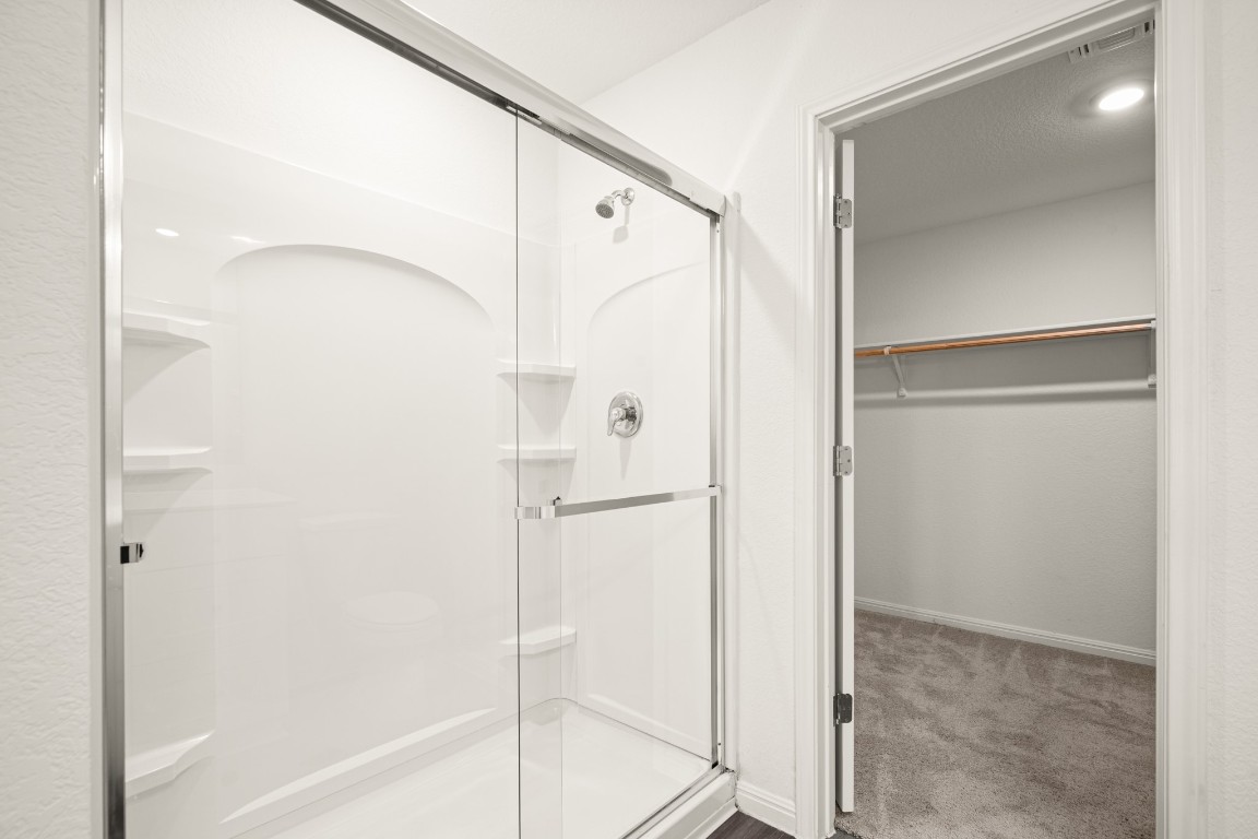 109 Gray Fox Loop Hutto, TX 78634 - Photo 13 of 28 Bathroom with a walk in closet, a shower stall, and carpet floors