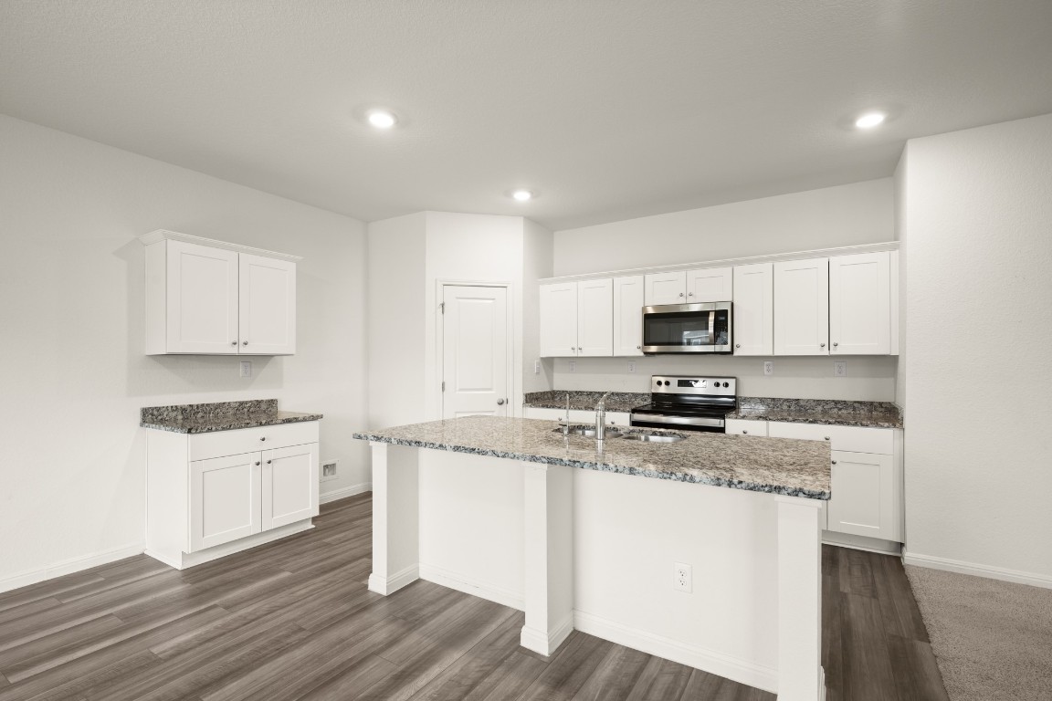 109 Gray Fox Loop Hutto, TX 78634 - Photo 2 of 28 Kitchen with white cabinetry, appliances with stainless steel finishes, light stone counters, a center island with sink, and recessed lighting