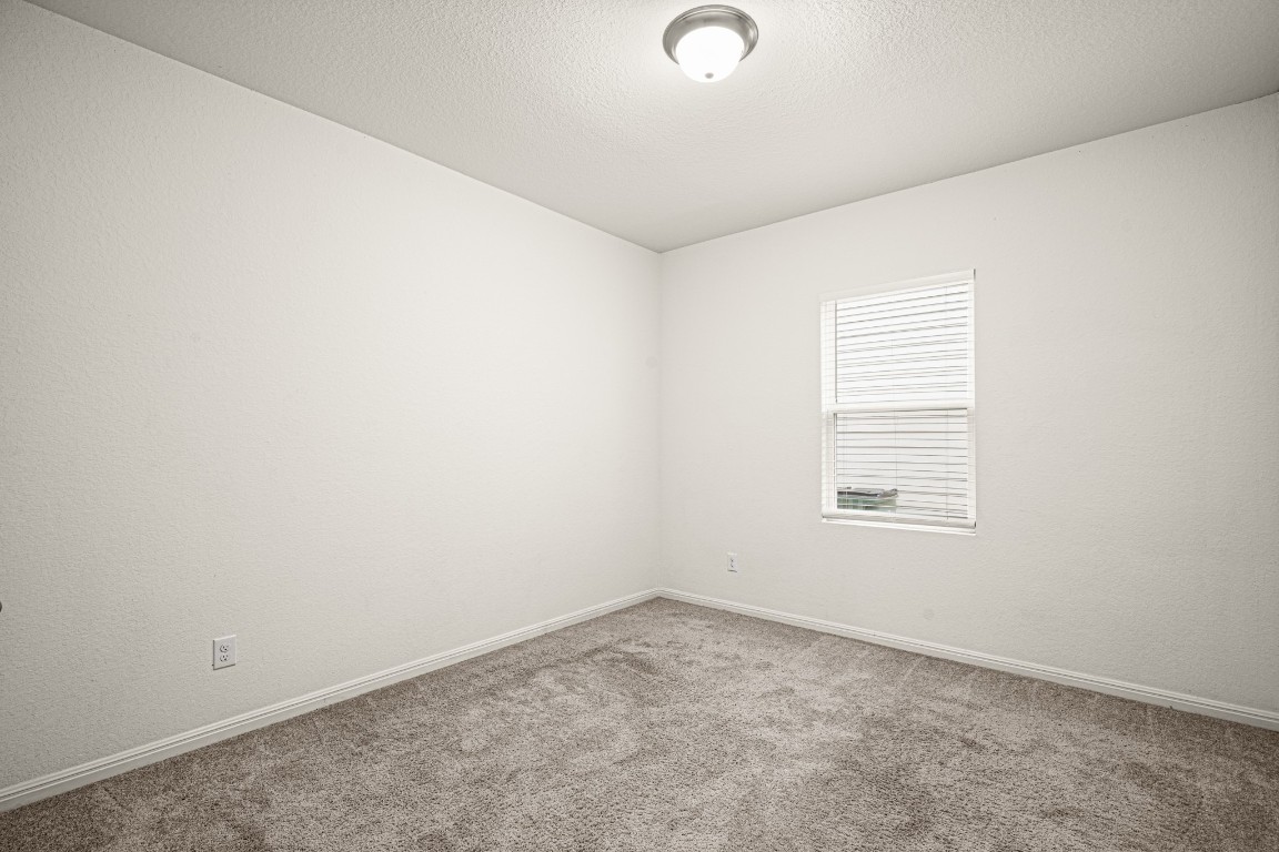 109 Gray Fox Loop Hutto, TX 78634 - Photo 17 of 28 Located upstairs, this bedroom features a textured ceiling and baseboards
