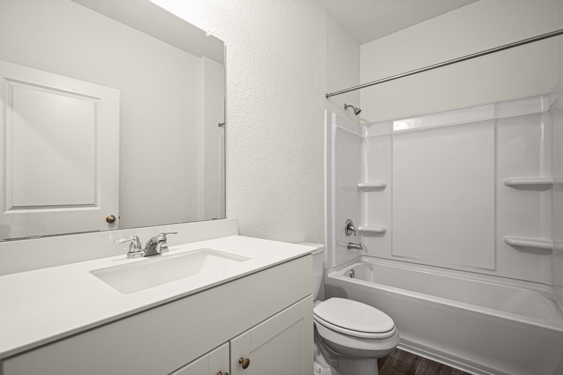 109 Gray Fox Loop Hutto, TX 78634 - Photo 5 of 28 Full downstairs bathroom with a textured wall, shower / bath combination, vanity, and dark wood-style floors