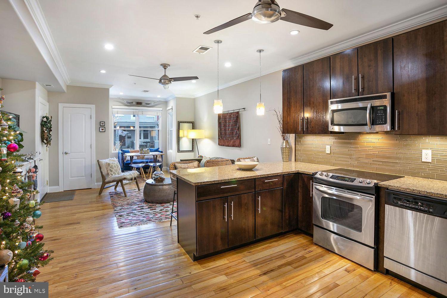 2650 15th Street Northwest, Unit 2 Washington, DC 20009 - Photo 6 of 25 a kitchen with stainless steel appliances kitchen island granite countertop a stove a sink a microwave and wooden floors
