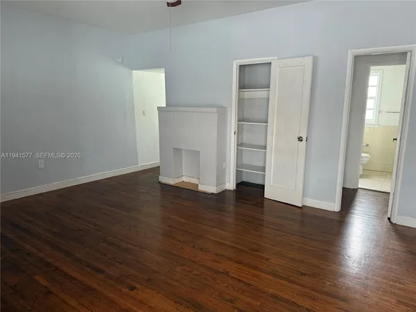 an empty room with wooden floor & closet and bathroom