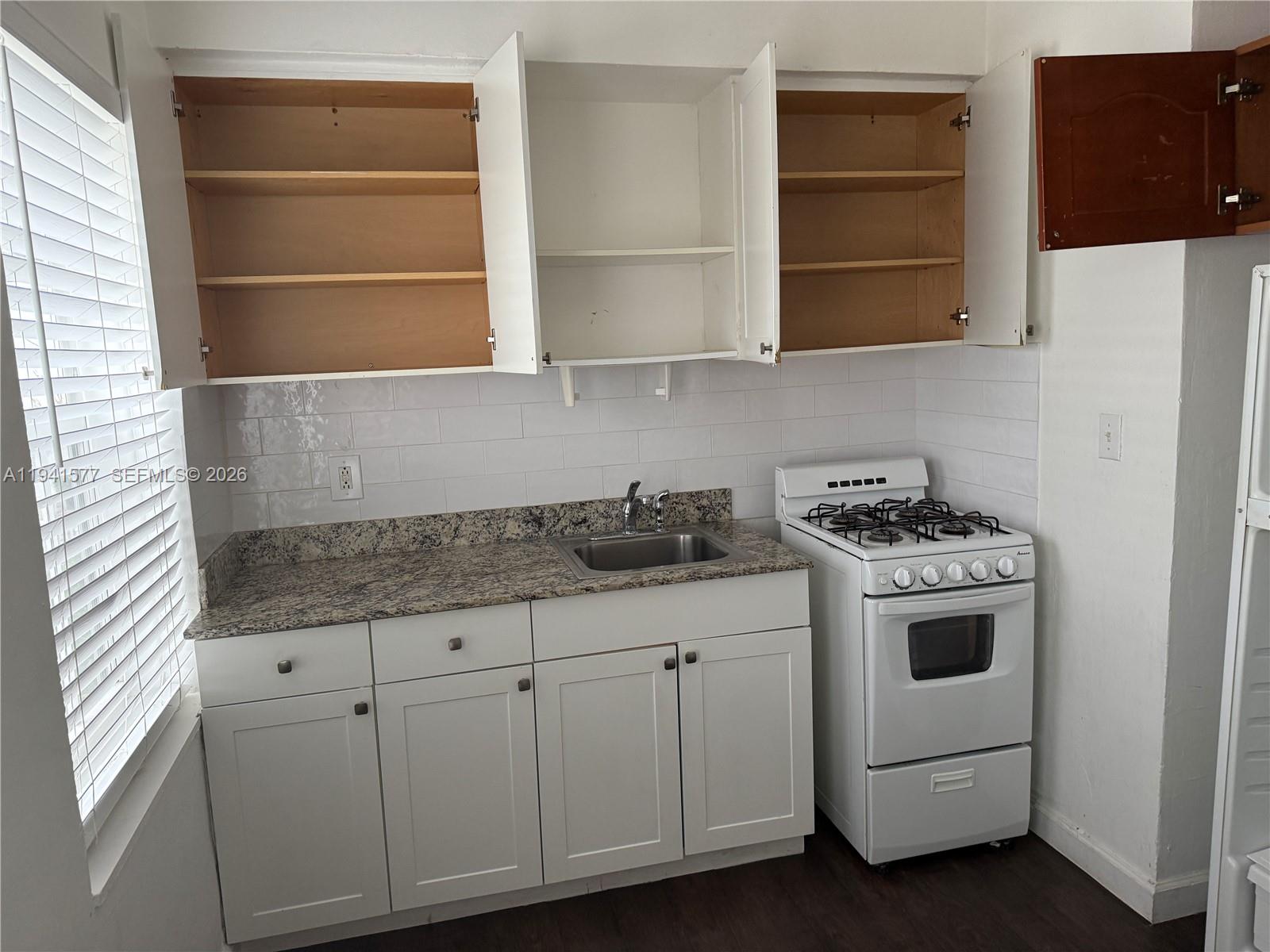 7611 Harding Avenue, Unit 7 Miami Beach, FL 33141 - Photo 10 of 11 a kitchen with granite countertop white cabinets and white appliances