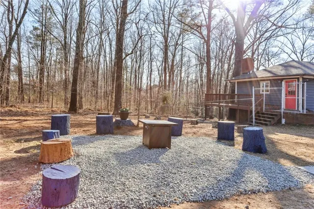 a view of a backyard with table and chairs potted plants and large tree