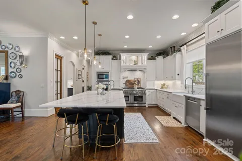 a kitchen with stainless steel appliances kitchen island granite countertop a table chairs refrigerator and microwave