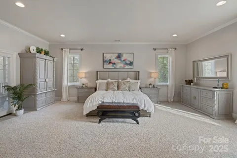 a spacious bedroom with a bed a couch and potted plant in it