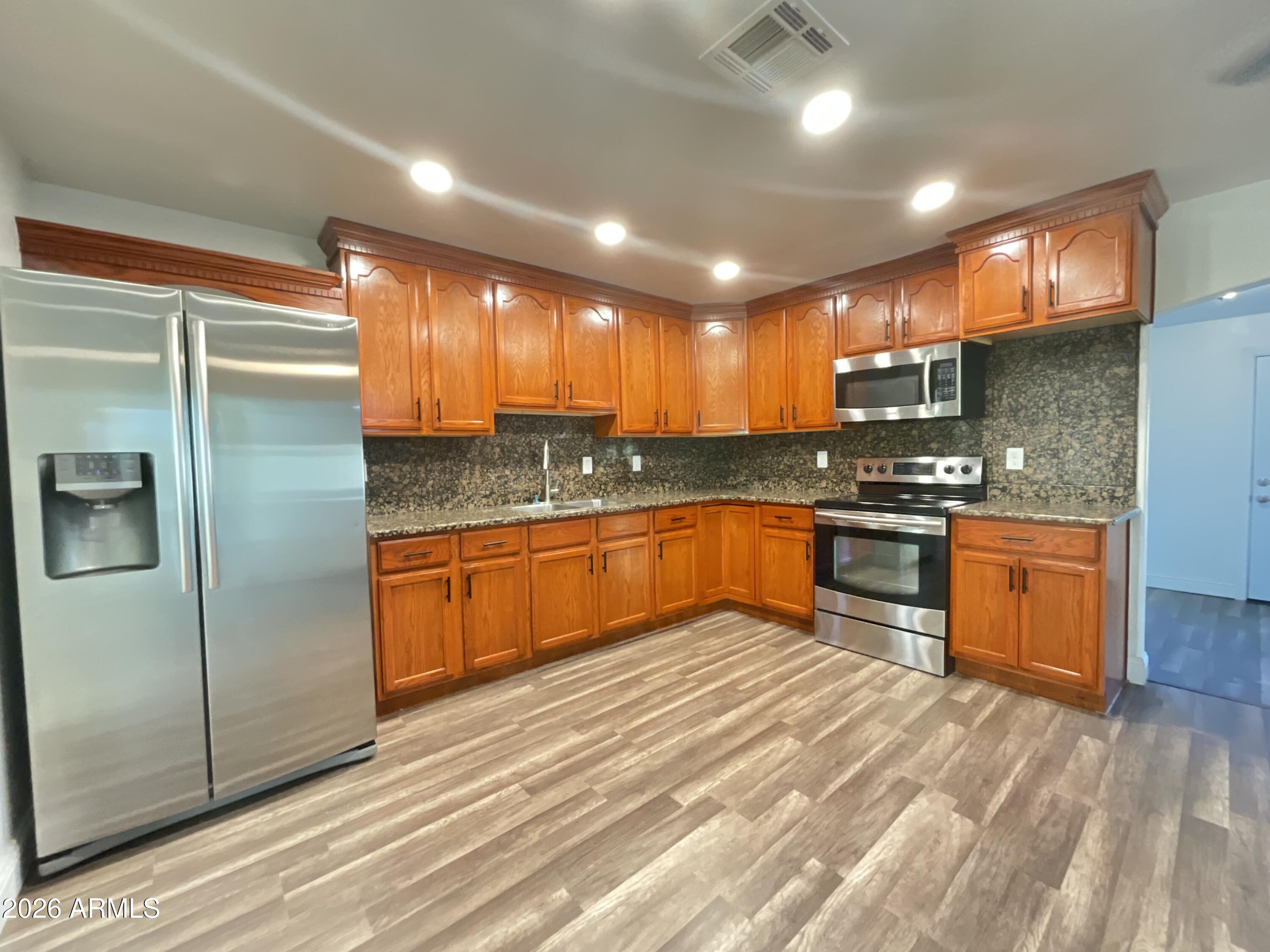 8052 West Pierson Street Phoenix, AZ 85033 - Photo 28 of 36 a kitchen with stainless steel appliances kitchen island granite countertop a stove a sink and a refrigerator