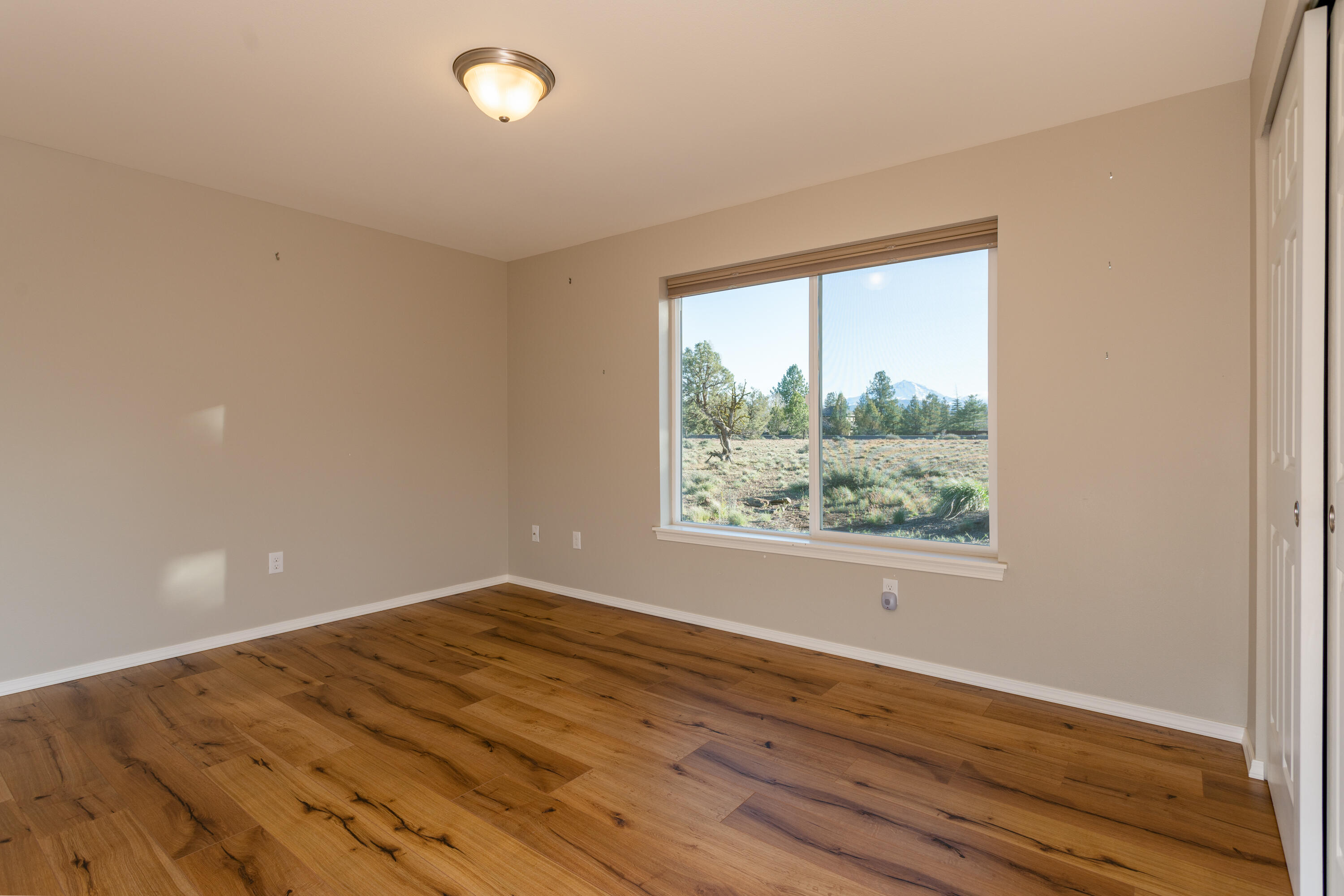 70099 Indian Ford Road Sisters, OR 97759 - Photo 21 of 27 a view of an empty room with wooden floor and a window