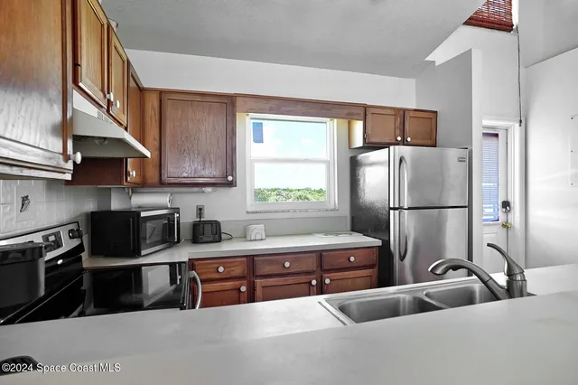 a kitchen with stainless steel appliances granite countertop a refrigerator a sink a stove and a refrigerator