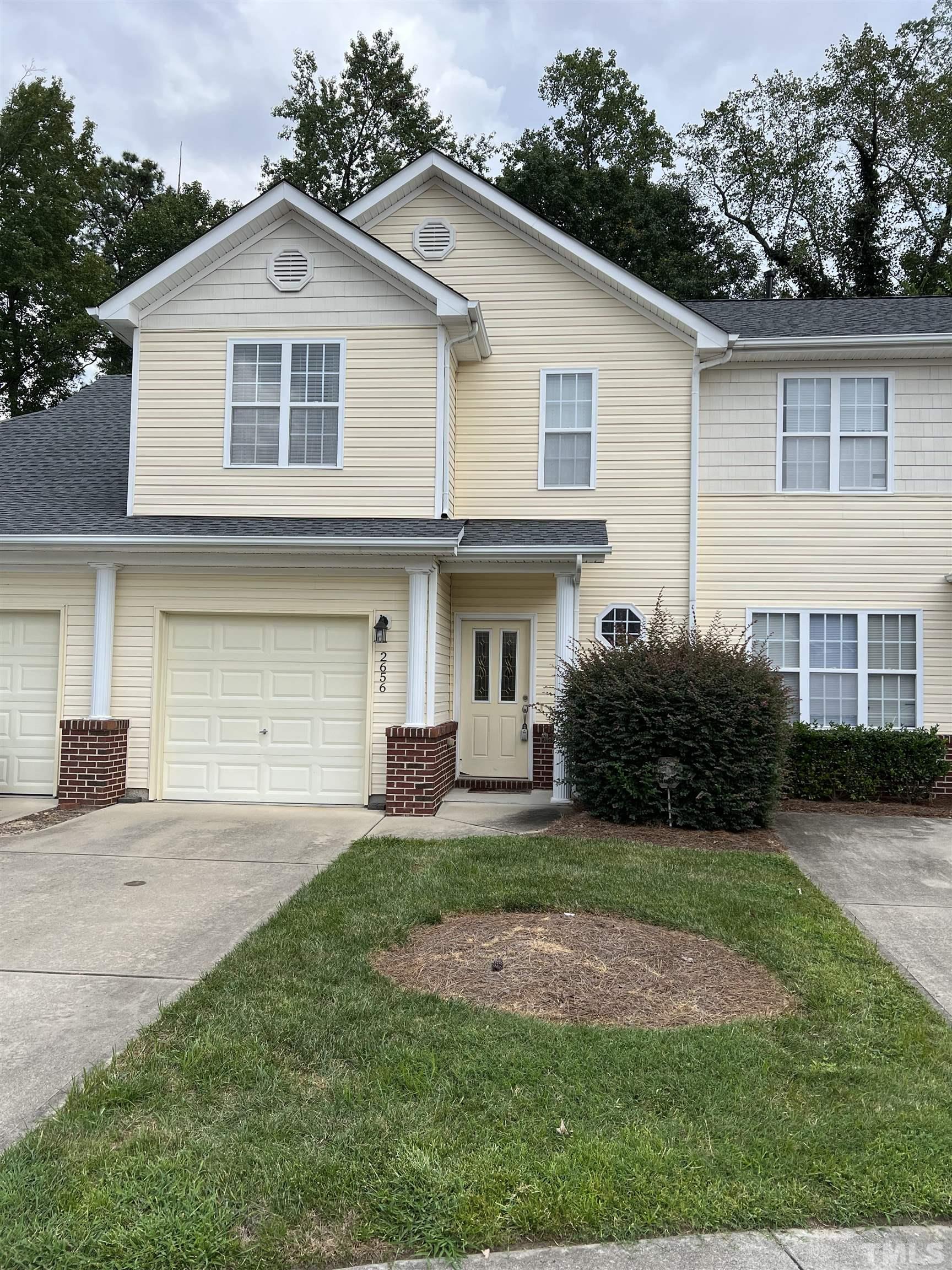 a front view of a house with a garden and trees