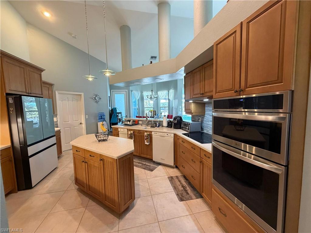 7791 Grande Pine Road Bokeelia, FL 33922 - Photo 44 of 45 a kitchen with stainless steel appliances kitchen island granite countertop a stove top oven a sink dishwasher and a refrigerator with wooden floor