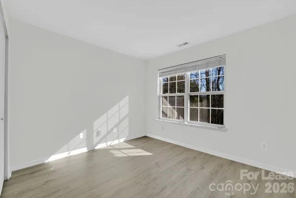 a view of an empty room with wooden floor and windows
