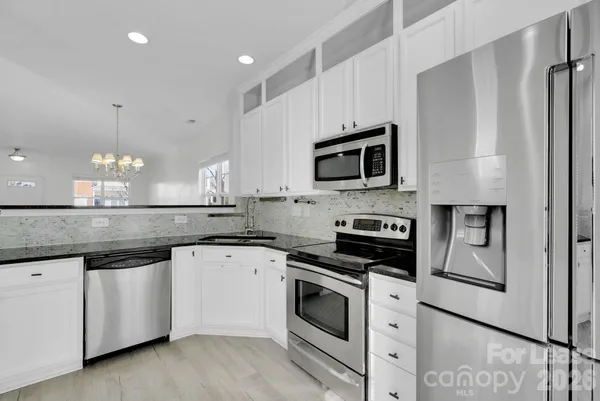 a kitchen with granite countertop white cabinets and stainless steel appliances
