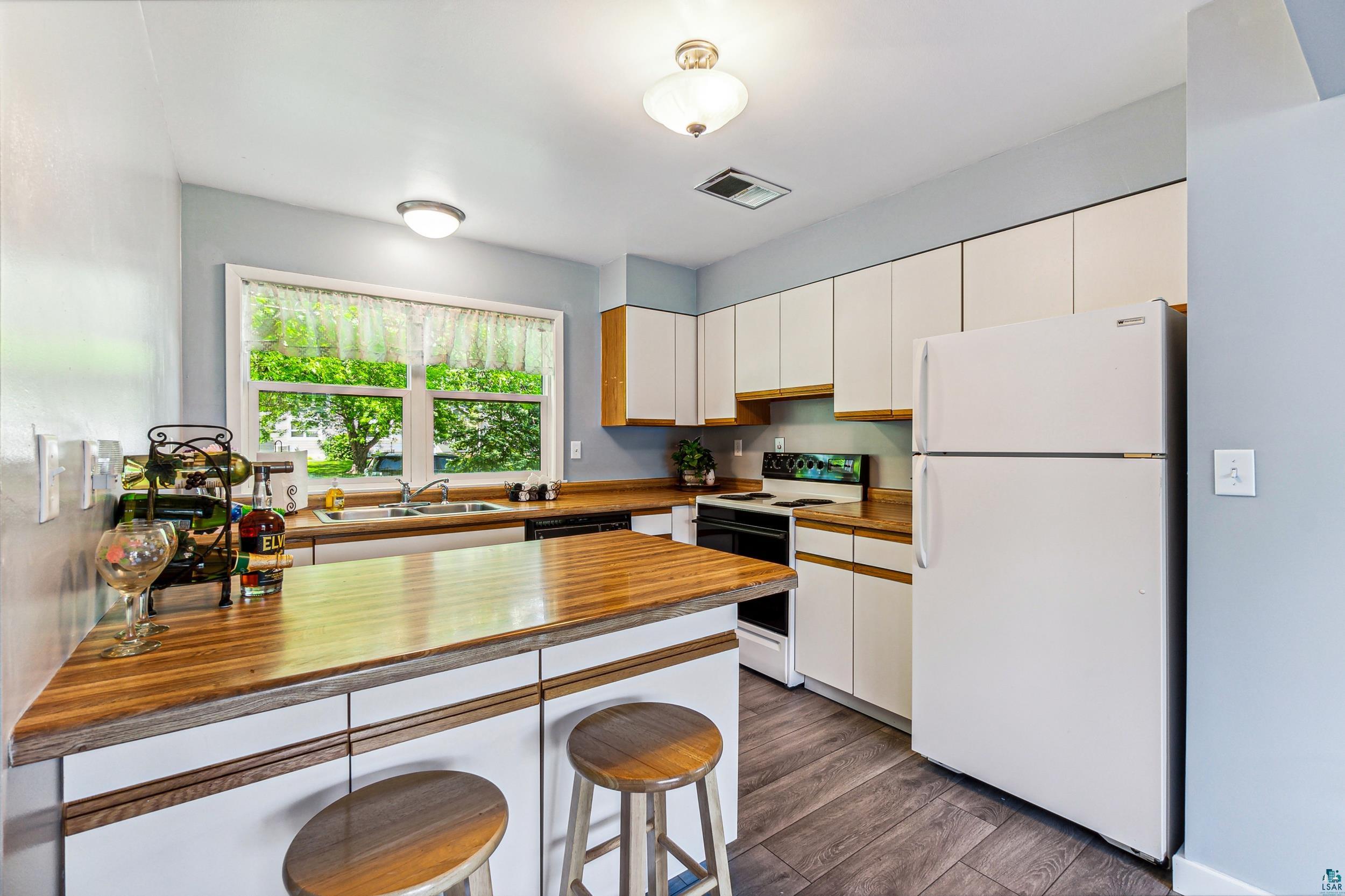 221 Mitchell Circle, Unit 52B Duluth, MN 55811 - Photo 12 of 27 Kitchen featuring dark hardwood / wood-style floors, white appliances, wooden counters, sink, and white cabinetry
