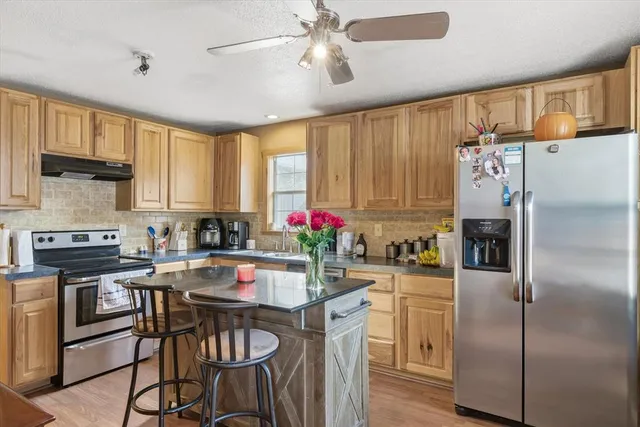 a kitchen with granite countertop a center island stainless steel appliances cabinets and a counter space