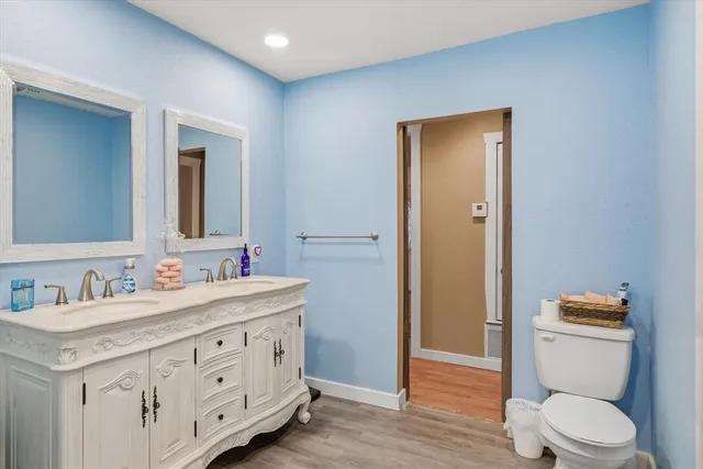 a spacious bathroom with a toilet a double vanity sink a mirror and a shower