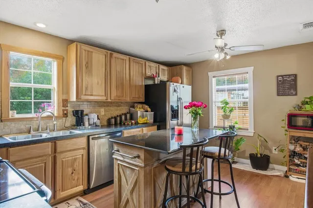 a kitchen with stainless steel appliances granite countertop a dining table chairs refrigerator and sink