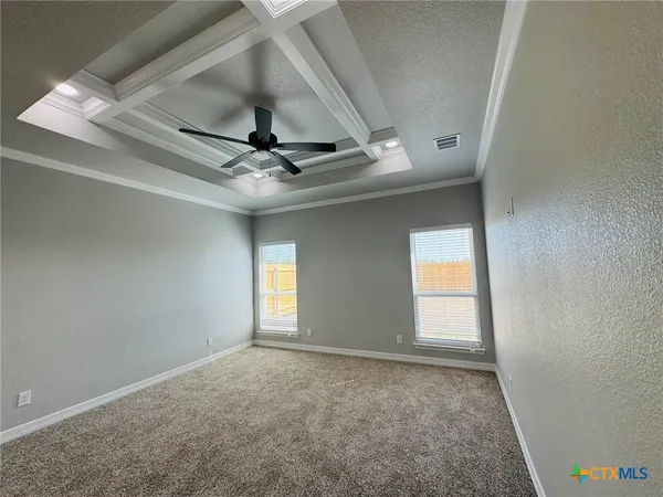 an empty room with windows and ceiling fan